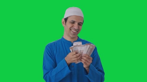 Happy Muslim man counting money Green screen