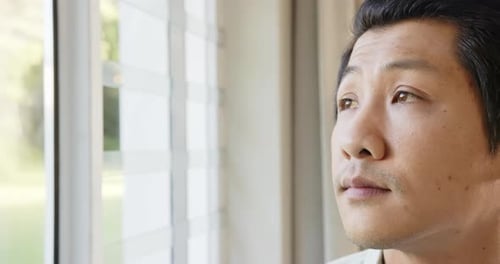Reflecting and contemplating, asian man looking out window, close-up portrait, copy space