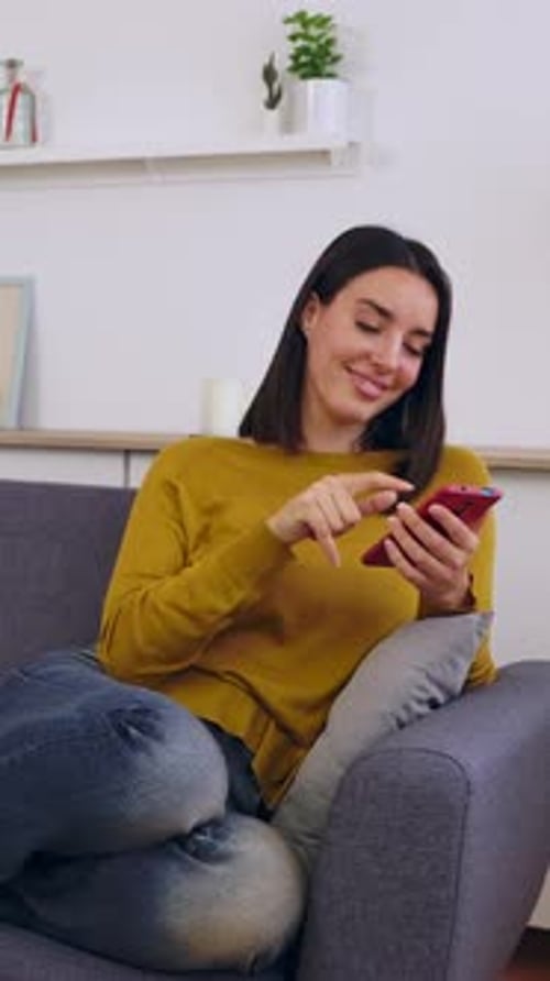 Woman Relaxing on Sofa Using Mobile Phone
