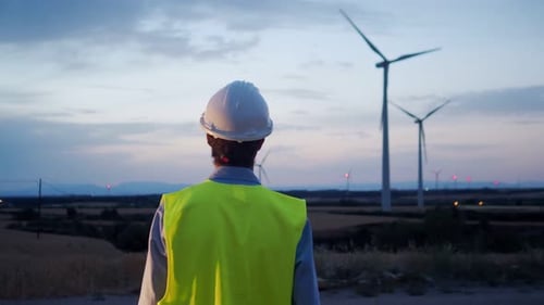Engineer Man From Behind Observing Windmills at Night
