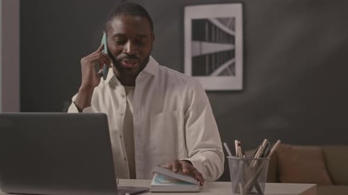 Man Working on Laptop and Talking on Phone