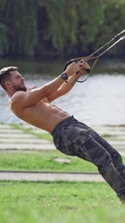 Athletic Man Exercising with Resistance Band Outdoors