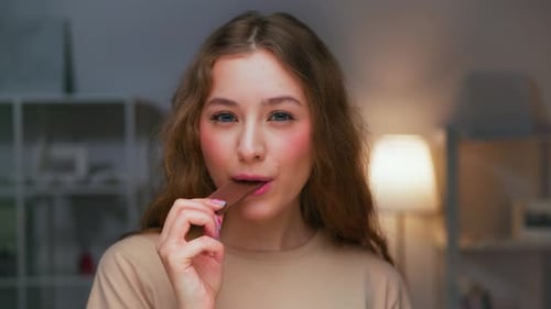 Portrait of Young Woman Eating Food of Sweet Chocolate Bar and Looking at Camera