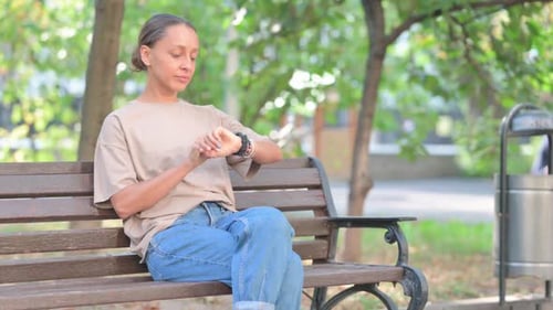Woman Checking Watch While Sitting on Park Bench