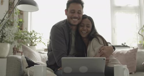 Smiling Couple Looking at Tablet on Couch