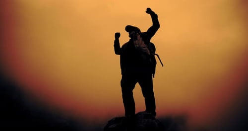 Silhouette of Person Celebrating on Mountain Peak at Sunset