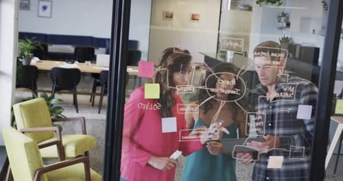 Diversos colegas criativos em discussão, fazendo anotações na parede de vidro no escritório, câmera lenta