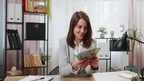 Empresária sorridente, contando dinheiro, dinheiro, verificando o salário, aproveite a riqueza na mesa do escritório doméstico
