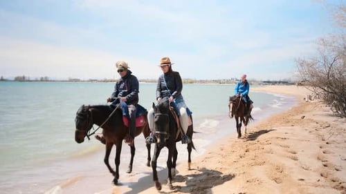 Tourists Horseback Riding Along a Lake Shore on a Sunny Day