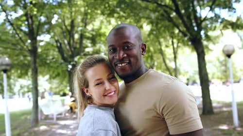 Pareja multirracial abrazándose en un parque público