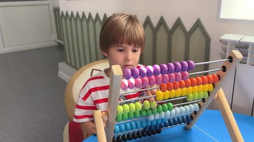 A Child Boy Toddler is Playing with Children's Abacus Counter or Settled Accounts