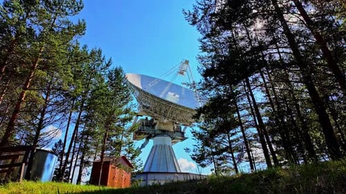 Vue extérieure du radiotélescope Irbene, dressé au milieu d'une forêt profonde, mettant en valeur son mas