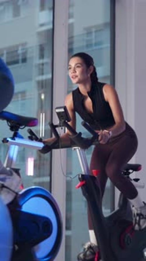 Exercise, spin class and woman on bike in gym for fitness, cardio workout and cycling for wellness