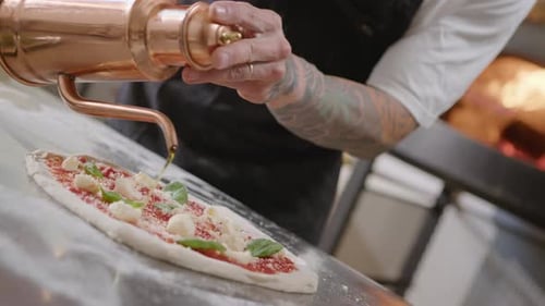 Chef Prepares Pizza with Oil Near Oven