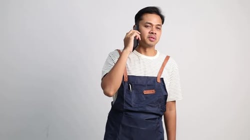 Restaurant or coffee shop waiters wearing aprons communicate and take customer orders via telephone.