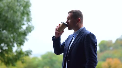 Portrait of One Successful Male Professional Standing Outdoors in Nature Drinking Coffee From Paper