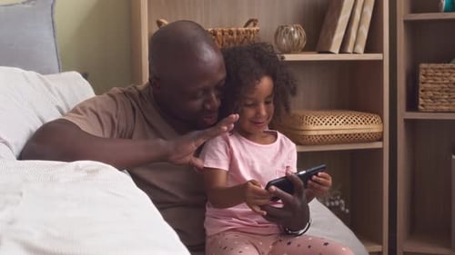 Father and Child Using Smartphone Together on Couch