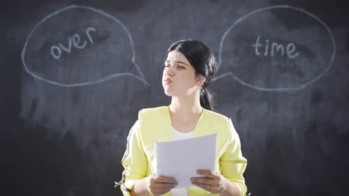 Woman Reads Document in Front of Chalkboard