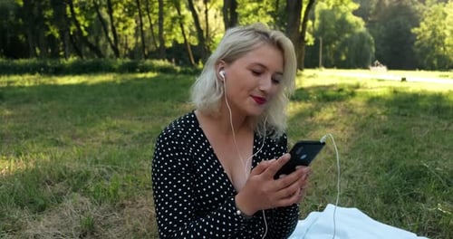 girl in the park listens to music on headphones