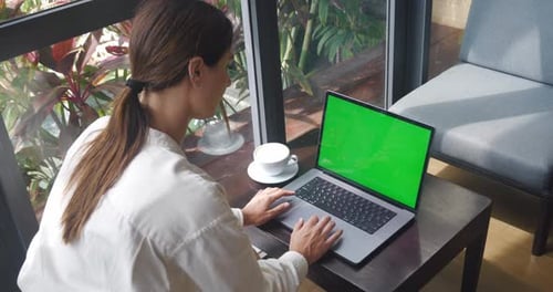 Young Woman Using Laptop with Green Screen While Sitting in Modern Cafe with Coffee Young Business
