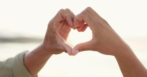 Couple, hands and heart emoji on beach for love, care or romance symbol or icon together outdoors