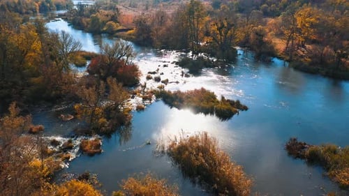 Beautiful nature in sun flare. Autumn scenery. Blue lake among yellow and orange trees.