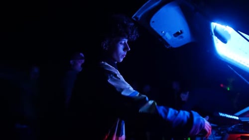 Jeune homme emballant un système Audio dans le compartiment de la voiture le soir après une fête de rue. Plan moyen