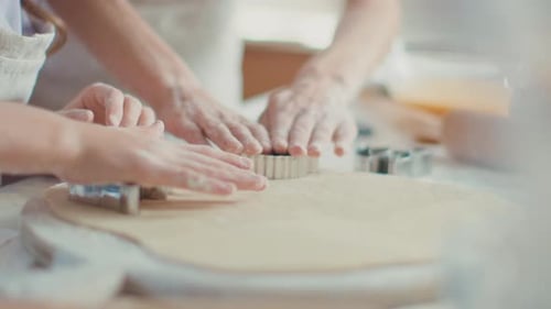 Close Up Woman and Girl Hands Cutting Dough with Cookie Cutters On