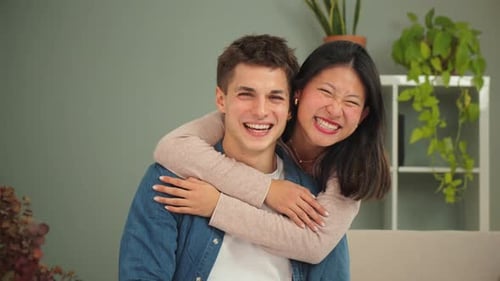 Close Up Portrait of a Real Multiethnic Couple Smiling Embracing and Looking at Camera Together Al