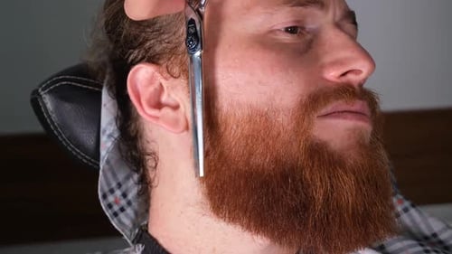 Barber Trimming Stylish Beard With Scissors and Comb