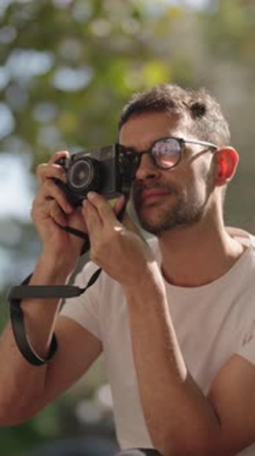 Young Man Taking Photos with a Vintage Camera in a Park