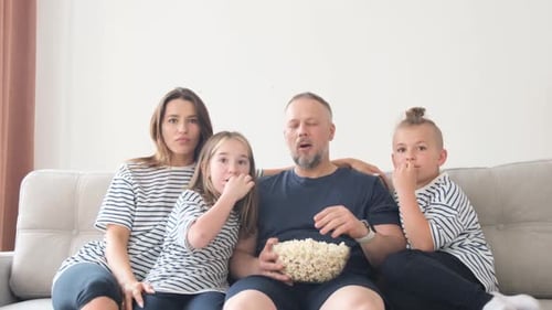 Family Watching TV and Eating Popcorn on Couch