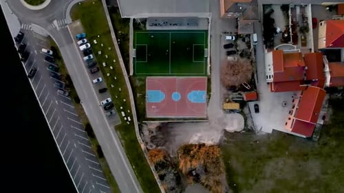 High Drone flight from bird's eye view over a small soccer field next to an basketball field where a