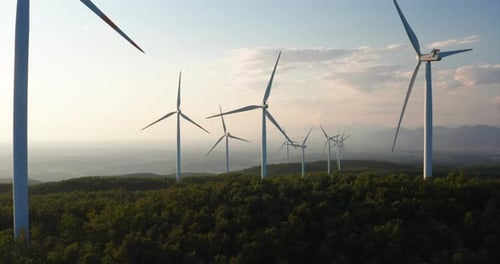 Aerial shot of wind mills rotating by the force of the wind and generating renewable energy in a g