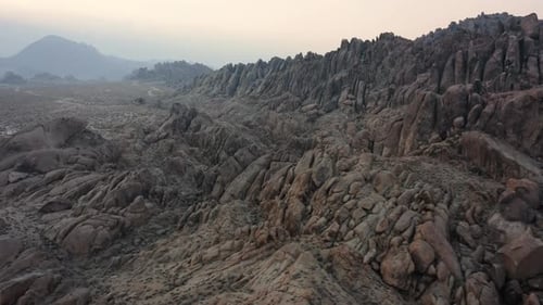 Cinematic drone view of an ancient rock formation on a foggy day