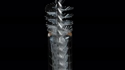 Die Reinigungsbürste tritt aus dem Glasrohr heraus und entfaltet ihre Kunststoffborsten. Makroaufnahme.