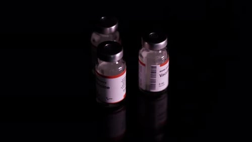Vaccine Vials on Reflective Black Surface