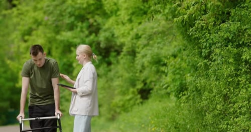 Man uses Walker with Helper on Nature Path