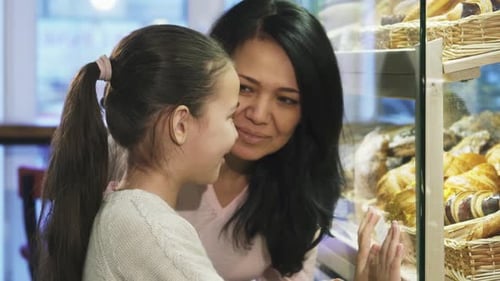 Mother and Daughter Joyfully Selecting Pastries at the Bakery Showcase