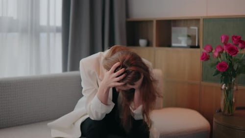 Sad Woman With Hands on Head Sits Couch