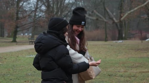 Mother and son share a fun moment feeding birds together in a park