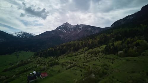 Hyperlapse aérienne : Alpes printanières, montagnes, nuages duveteux, prairies verdoyantes et arbres en fleurs dans la vallée