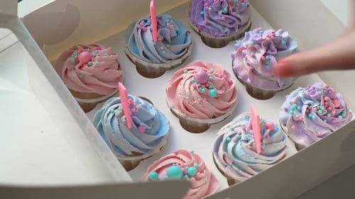 Hand Reaching for Frosted Cupcake with Birthday Candle