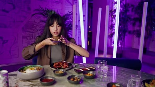 a young girl takes a picture on a smartphone of serving a dish in a teapot in a Korean restaurant
