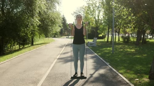 Young Brunette Woman Using Resistance Bands for Outdoor Fitness Training in the Park