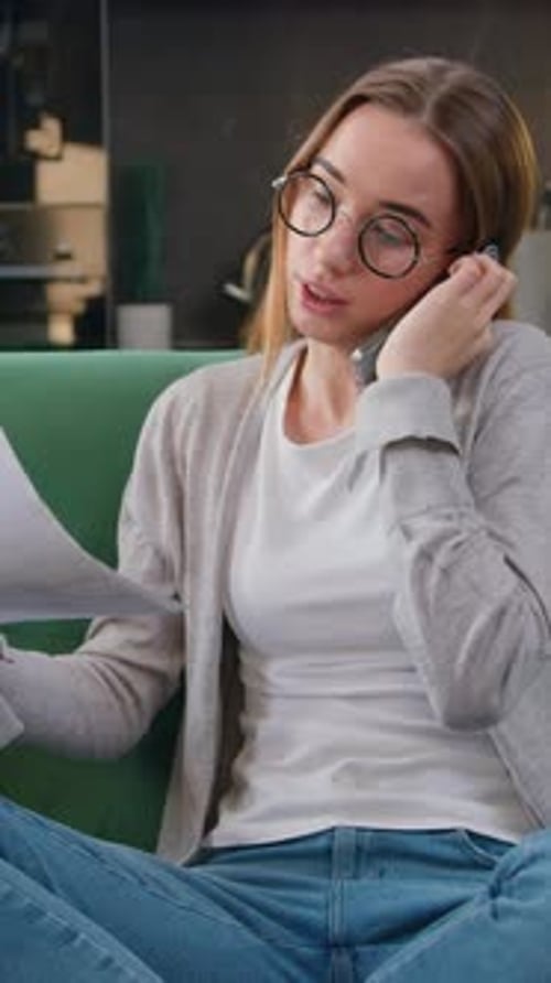 Good Looking Caucasian Girl Working with Smartphone and Documents Collating Data and Checking