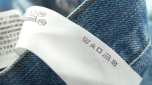 Close up of clothing care label on denim fabric with washing symbols
