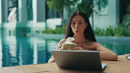 Young Woman Watching Video Via Laptop Bathing in Pool