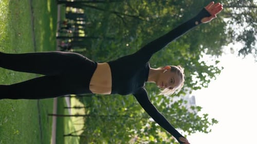 vertical video A girl athlete performs jumping exercises as a warm-up before training on the street
