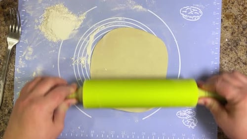 Rolling out round pieces of raw dough with a rolling pin to make patties. Top view.